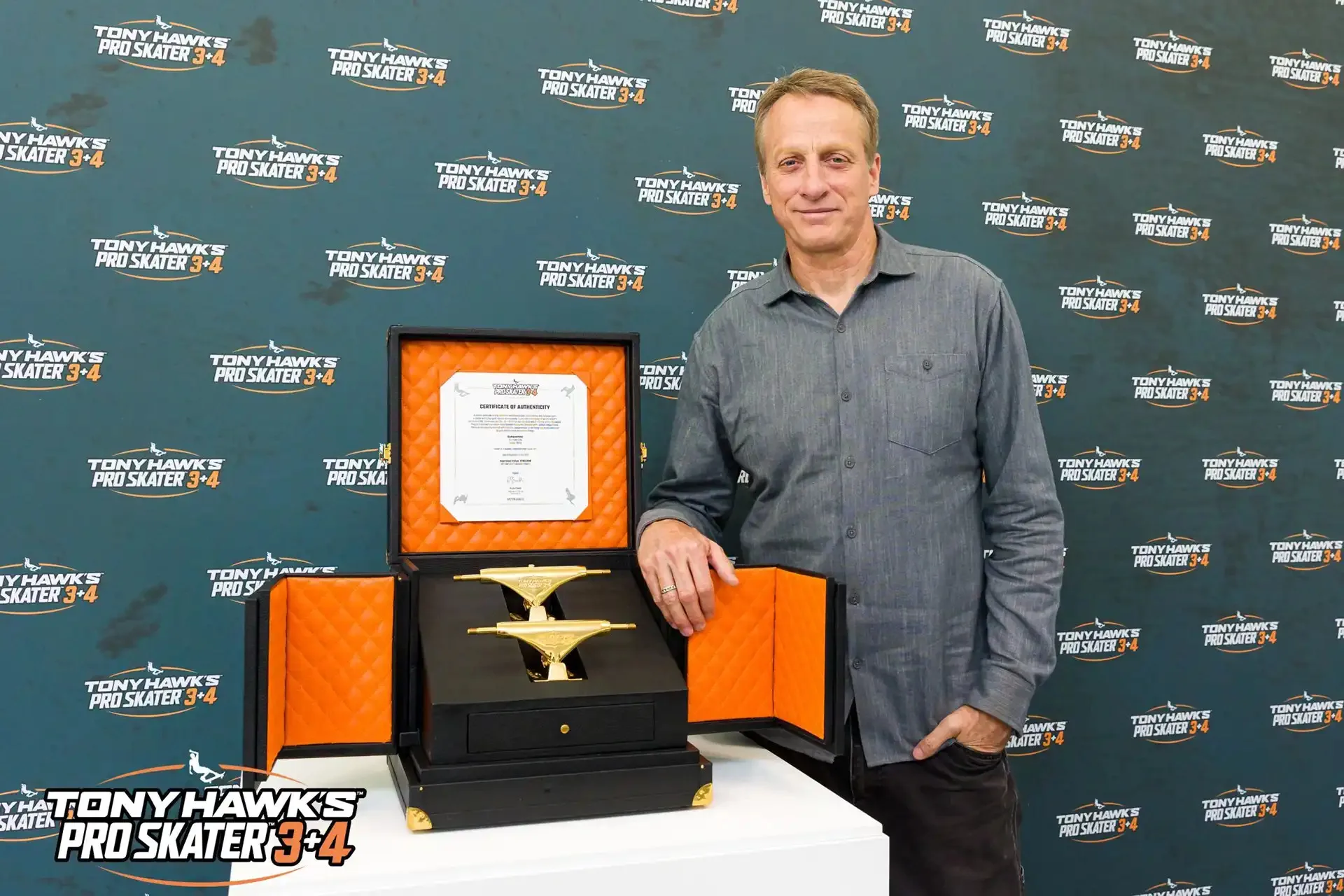 Tony Hawk next to the golden trucks and their display box
